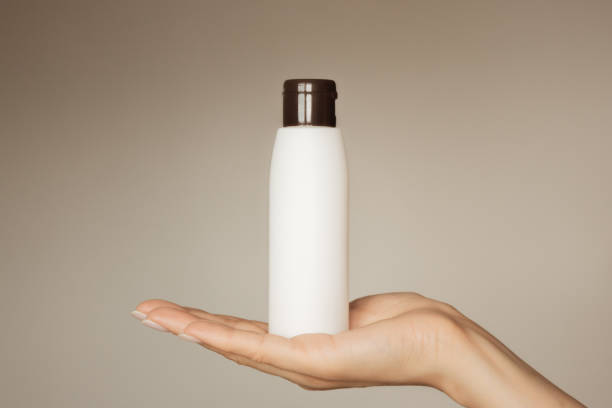 istock a woman's hand holds a white cosmetic bottle with a brown lid 1695412673