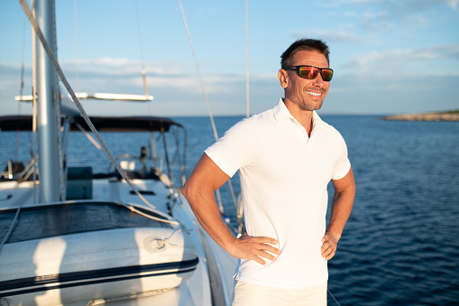 Good life. Confident handosme man in sunglasses on a yacht