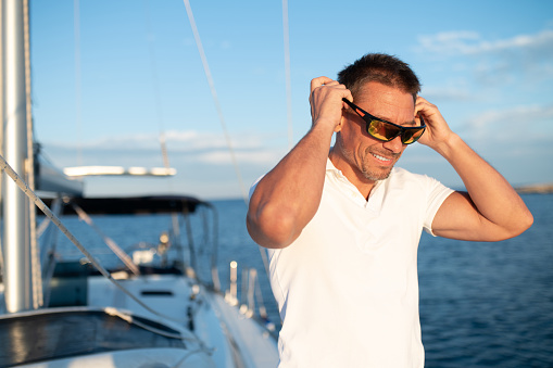 Good life. Confident handosme man in sunglasses on a yacht