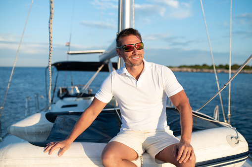 Good life. Confident handosme man in sunglasses on a yacht