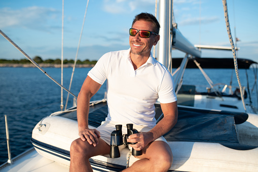 Good life. Confident handosme man in sunglasses on a yacht