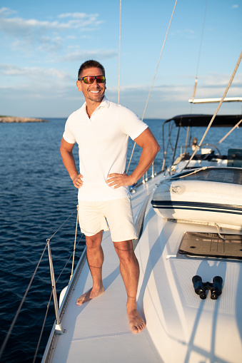 Good life. Confident handosme man in sunglasses on a yacht