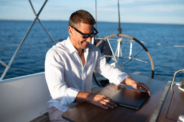 istock Confident man in sunglasses working on a laptop while sailing on a yacht 1695440135