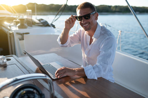 istock Confident man in sunglasses working on a laptop while sailing on a yacht 1695440653