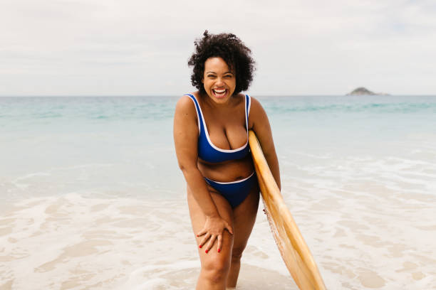 istock Excited surfer having fun on a beach vacation, wearing a bikini and holding a surfboard 1695442350