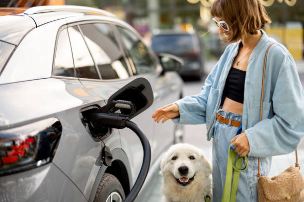 istock Woman with dog pulling a charging plug out of her EV car, 1695446155