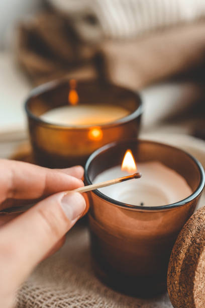 Match in hand lights a candle, cosiness concept