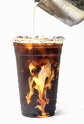 Iced cold brew coffee in a glass with milk poured over.