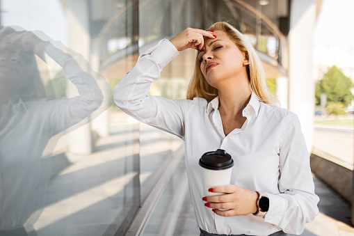 Business woman in morning time, holding her coffee and feeling tired