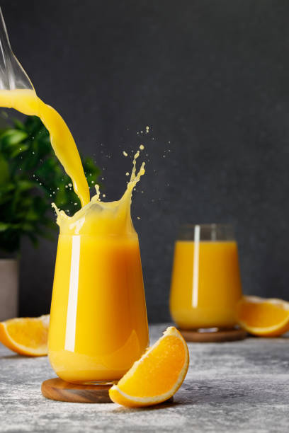istock orange juice pouring into glass with splash on table 1695497605