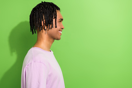 Profile photo of funny cheerful guy looking empty space hipster style braids wear oversize shirt isolated green color background.
