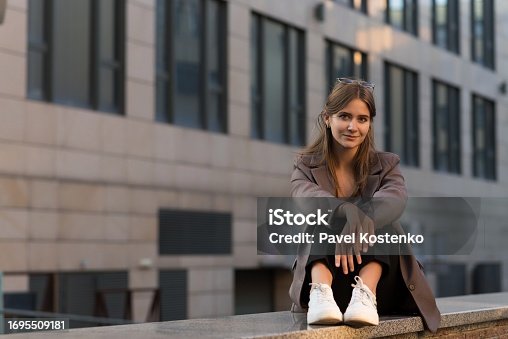 Portrait of a Caucasian attractive and happy young woman in casual clothes and sunglasses in the city while walking on a sunny day. The concept of style, fashion, youth and lifestyle