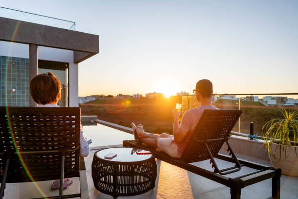 istock Mature friends sitting in deck chairs and watching the sunset 1695516495