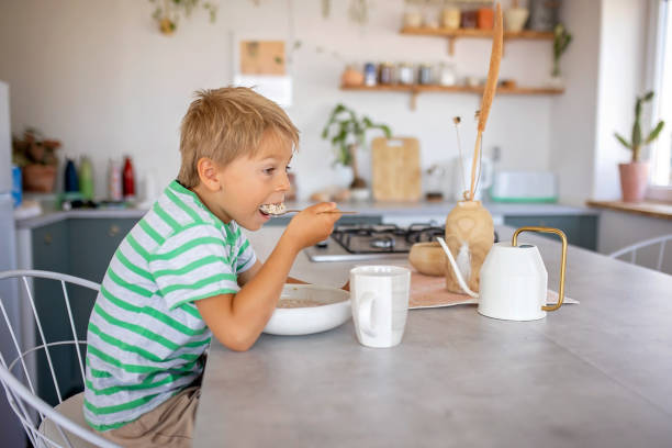 아름 다운 금발 아이, 소년, 아침에 집에서 아침 식사로 시리얼을 먹고 있습니다 - eating cereal student human mouth 뉴스 사진 이미지