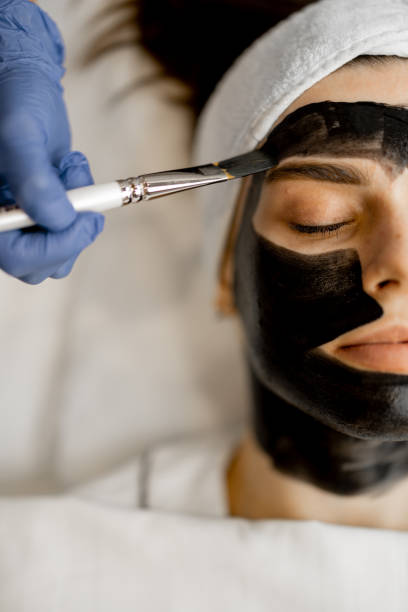 istock Applying carbon mask to a woman's face 1695538068