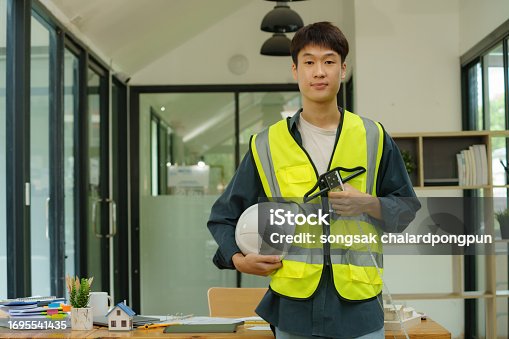 Portrait of an Asian male engineer standing near a desk in the office.