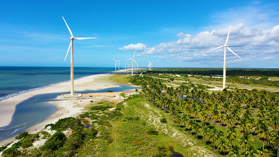 Northeast Brazil. Aeolian turbine at Beach at Ceara state. Beach with sand dunes and desert landscape. Power generation. Green energy. Wind farm field.