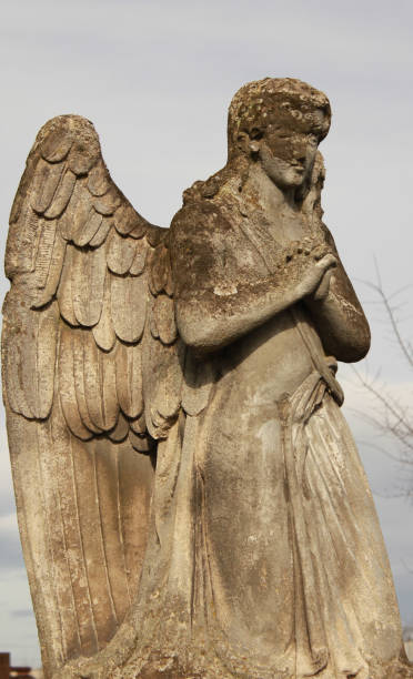 istock Figure of a praying angel on a blue sky 1695570255