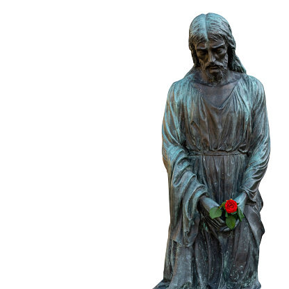 An ancient statue of Jesus Christ with rose flower in hands. Isolated on white backgrouund.