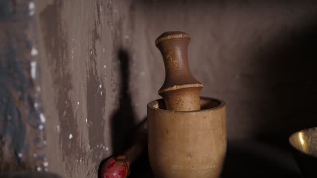 Close-up of a wooden mortar for grinding spices on a shelf in an old antique hut
