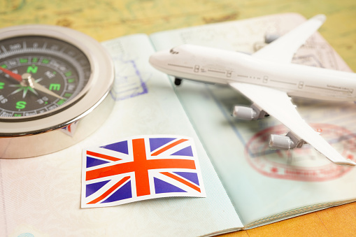 United Kingdom flag with vintage compass and airplane on world map.