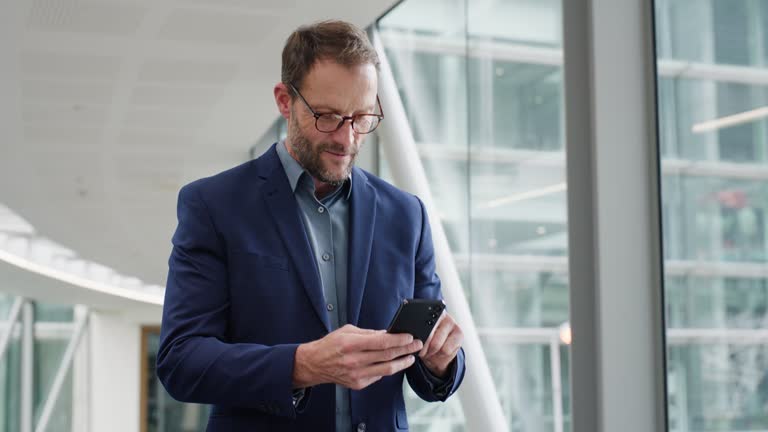 Walking, phone and happy business man in building on commute, travel and journey in corridor. Corporate, professional and worker on smartphone for social media, internet and planning on mobile app