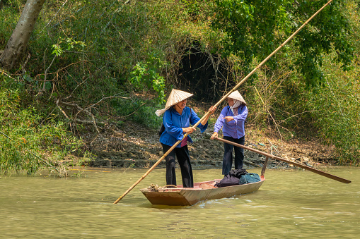 Two Vietnamese women in traditional clothing on a small wooden boat. Ba Be National Park, North Vietnam.\nThe name Ba Ba translates as Three Lakes, referring to the three parts of the lake: Pe Leng, Pe Lu, and Pe Lam. The lake is the largest freshwater lake in Vietnam spanning over 500ha. It is also the highest, sitting at 150 meters above sea level. The vast lake is surrounded by impressive karst peaks that make up the Pia Booc mountain range and thick, evergreen forests.