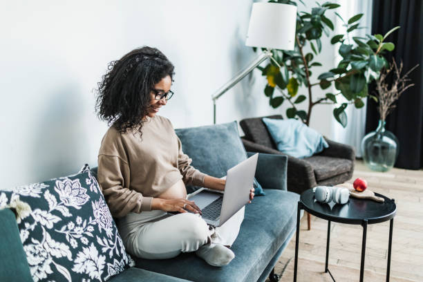 istock Pregnant black woman working from home using laptop, having video call with colleagues 1695673122