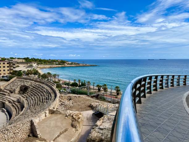 beach with history of tarragona on the coast of the mediterranean sea in spain holidays palm trees tropical tourist destination hotels and buildings facing the sea and historic ruins