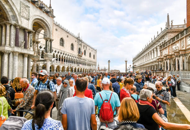 The visible effects of overtourism as cruise ship passengers crowd the walkway at the Doge's Palace in Piazza San Marco on a busy day in Venice, Italy The visible effects of overtourism as cruise ship passengers crowd the walkway at the Doge's Palace in Piazza San Marco on a busy day in Venice, Italy walking point of view stock pictures, royalty-free photos & images