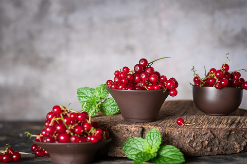 Red, currant in a small bowls on a rustic wooden background.Ripe summer berry,garden berries or harvesting concept