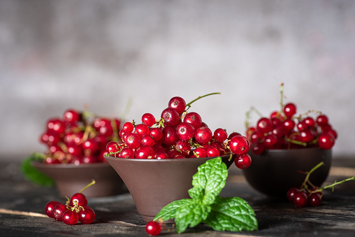 Red, currant in a small bowls on a rustic wooden background.Ripe summer berry,garden berries or harvesting concept