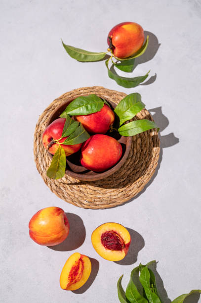 сочные и сладкие нектарины в миске на светлом фоне с тенью. концепция здоровых фермерских фруктов. - georgia peach стоковые фото и изображения