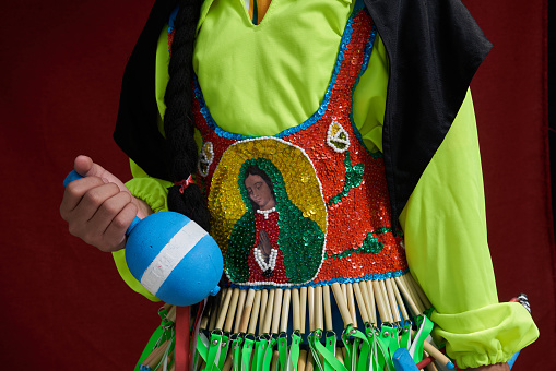 Mexican Danza Maraca held by dancer wearing traditional Danza Regalia with the Virgin Mary on their chest