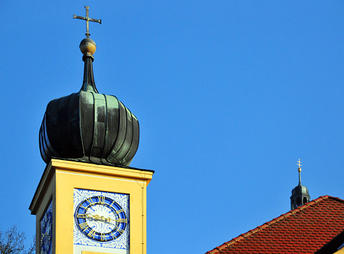 Freising, Bavaria, Germany: Vinzentinum clock tower with onion dome and cross, Altötting Chapel (1669), branch church of the parish church of St. George - baroque building on the south side of the Domberg / Cathedral Hill, on Brunnhausgasse. Usually made of copper sheet, onion domes appear on Catholic churches all over southern Germany, Czechia and Austria. Onion domes are popularly believed to symbolize burning candles.