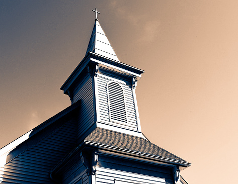 Southern style white exterior Christian church steeple in Georgia against moody artistic sky with deep shadows on side