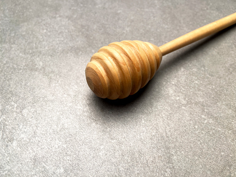 Wooden honey dipper on gray ceramics background with copy space