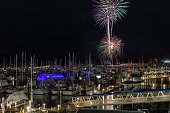 Fireworks at midnight to celebrate the New Year during Alaskan winter over Seward, Alaska harbor with dock lights on and boats and ships