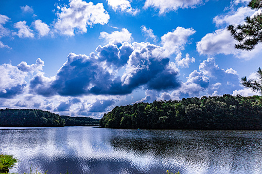 Majestic West Point Lake in Georgia, surrounded by trees with reflection of clouds and sky in still lake water