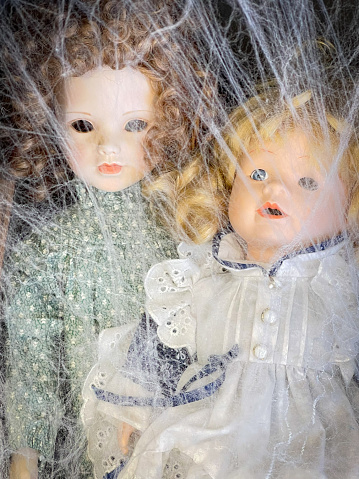 Two old broken dolls with cobwebs