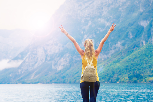 Travel, adventure, tourism- Mountain lake and happy hiker woman with arms up