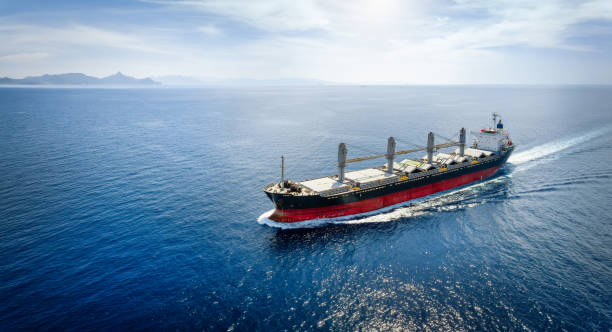 Aerial view of a bulk carrier cargo vessel traveling with high speed over blue sea Aerial view of a bulk carrier cargo vessel traveling with high speed over blue sea with copy space as a concept for import and export industry bulk carrier stock pictures, royalty-free photos & images