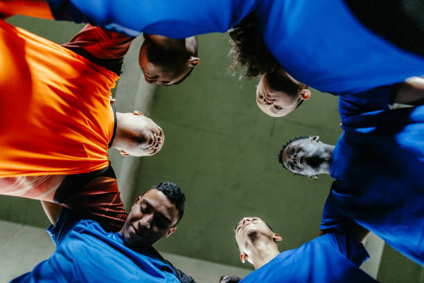 soccer team huddling on the soccer field - exercising motivation looking up african descent photos et images de collection