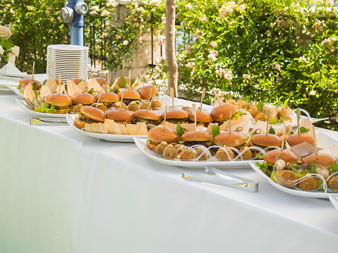 Banquet table with snacks food on plates hamburger party dinner table - buffet table after wedding ceremony concept