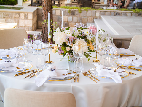 Beautiful outdoor wedding decoration in city. Candles and dried flowers and accessories with bouquets and glasses on table with linen tablecloth on newlywed table on lawn