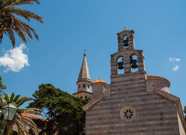 campanili del tempio cattolico e ortodosso nella città vecchia stari grad di budva, montenegro. la torre della chiesa di san ivan e il campanile della chiesa della santissima trinità, primo piano - church bell tower temple catholicism foto e immagini stock