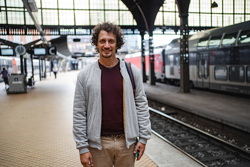Portrait of a Caucasian men with curly brown hair at the train station