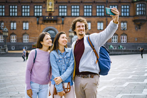 istock Three smiling tourists taking selfies while exploring the city of Copenhagen 1695861508