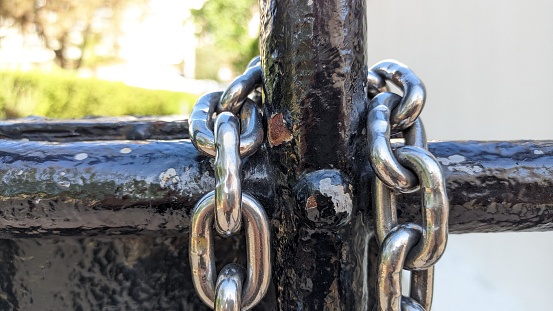 A new thick, strong and shiny chain hangs on the old black gate photo