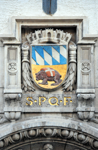 Freising, Bavaria, Germany: stone carved municipal oat of arms above the main gate of the city hall (Rathaus), displaying the Bavarian blue lozenge pattern and a bear with a white cross on red background, below it the Rome inspired Latin inscription, SPQF, Senatus Populusque Frisingensis - Marienplatz, in Freising's old town.